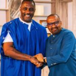 Two people smiling and shaking hands indoors.