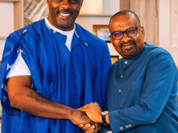Two people smiling and shaking hands indoors.