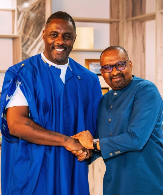 Two people smiling and shaking hands indoors.