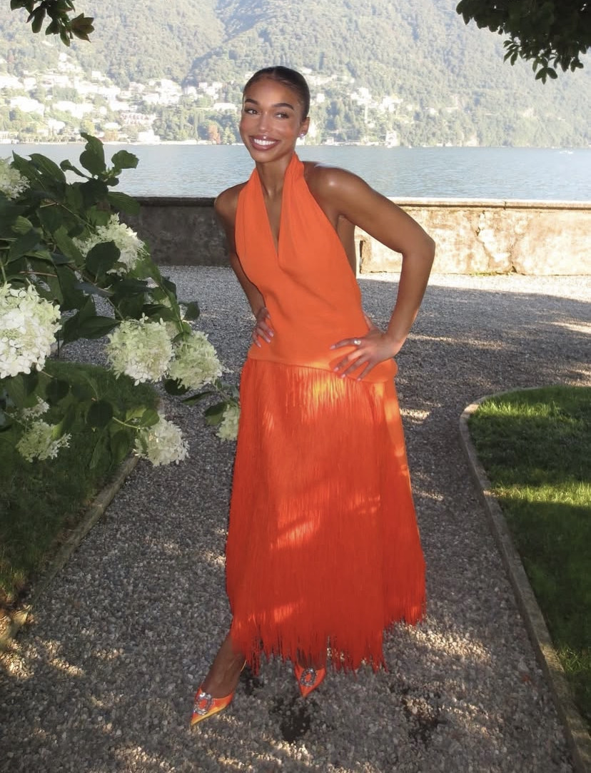 Lori Harvey in orange halterneck gown with tiered fringe skirt