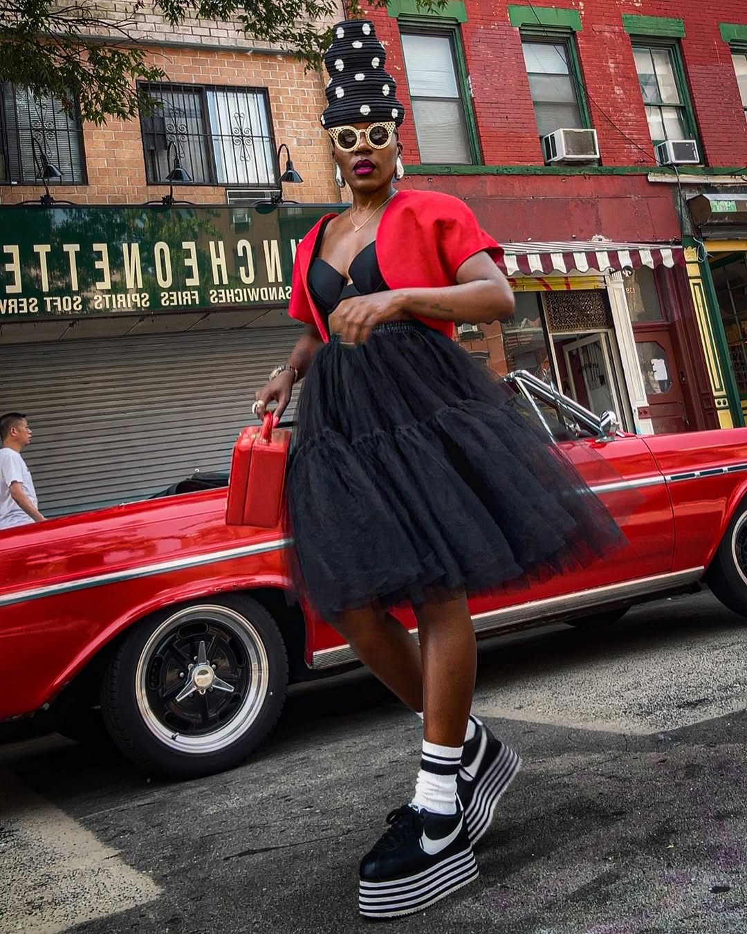 woman wearing black dress with red jacket and black sneakers
