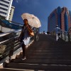 A woman uses an umbrella for shade during a heatwave in Shanghai, illustrating the increasing frequency and intensity of heatwaves linked to fossil fuel emissions.