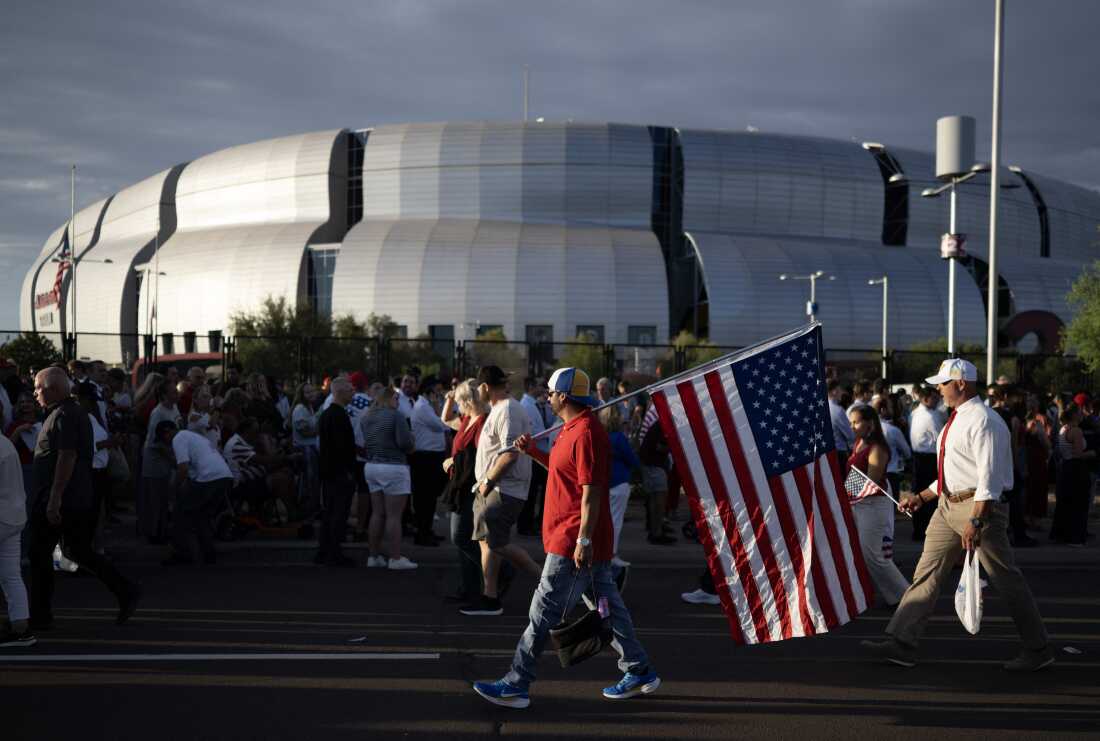 Man carrying U.S. flag arriving at Charlie Kirk's memorial in Glendale, Arizona