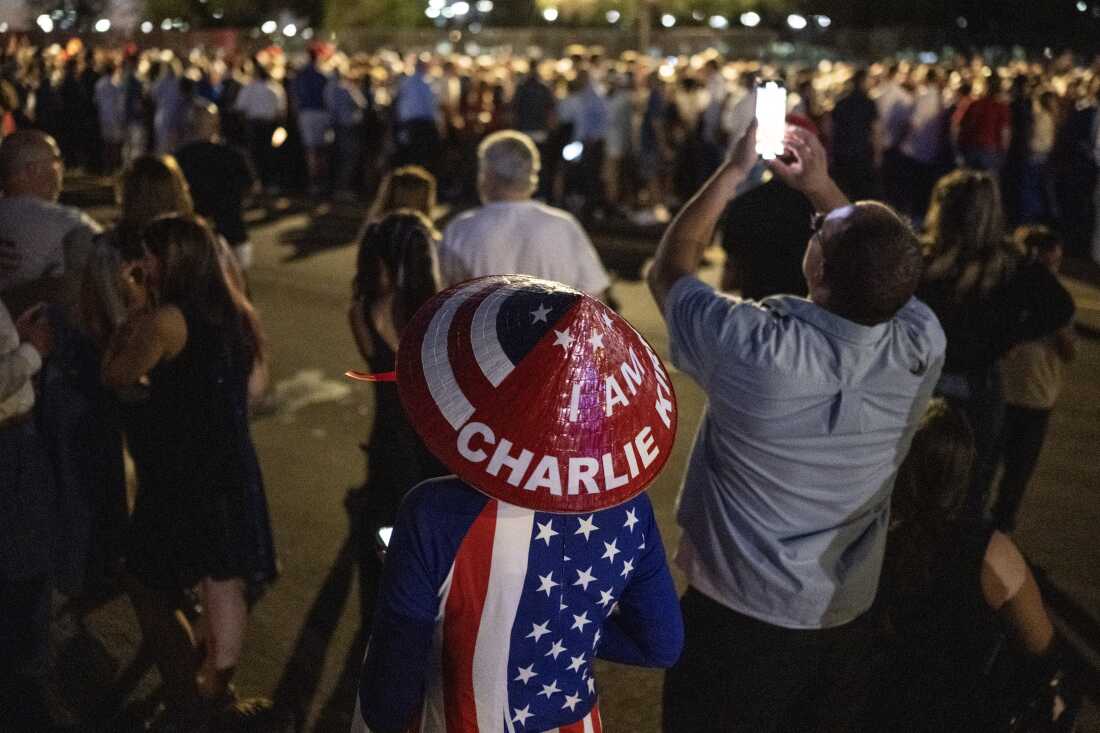 Individual wearing 'I am Charlie Kirk' hat at memorial service in Glendale, Arizona