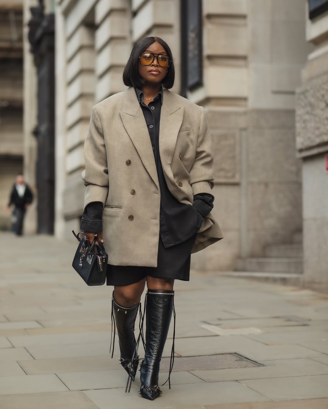 woman wearing black shirt with matching shorts and a coat, black leather bag and boots