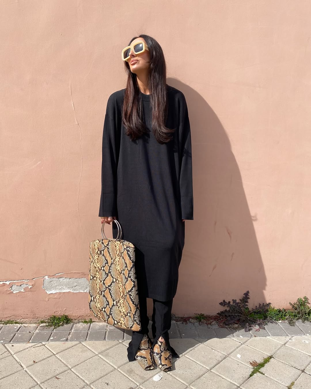 woman wearing black dress with snakeskin boots and matching tote