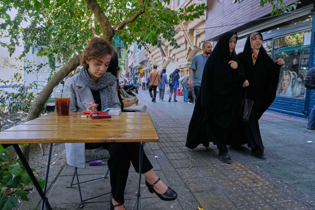 A woman seated at an outdoor café on Enqelab-e-Eslami street in Tehran, Sept. 27, 2025.
