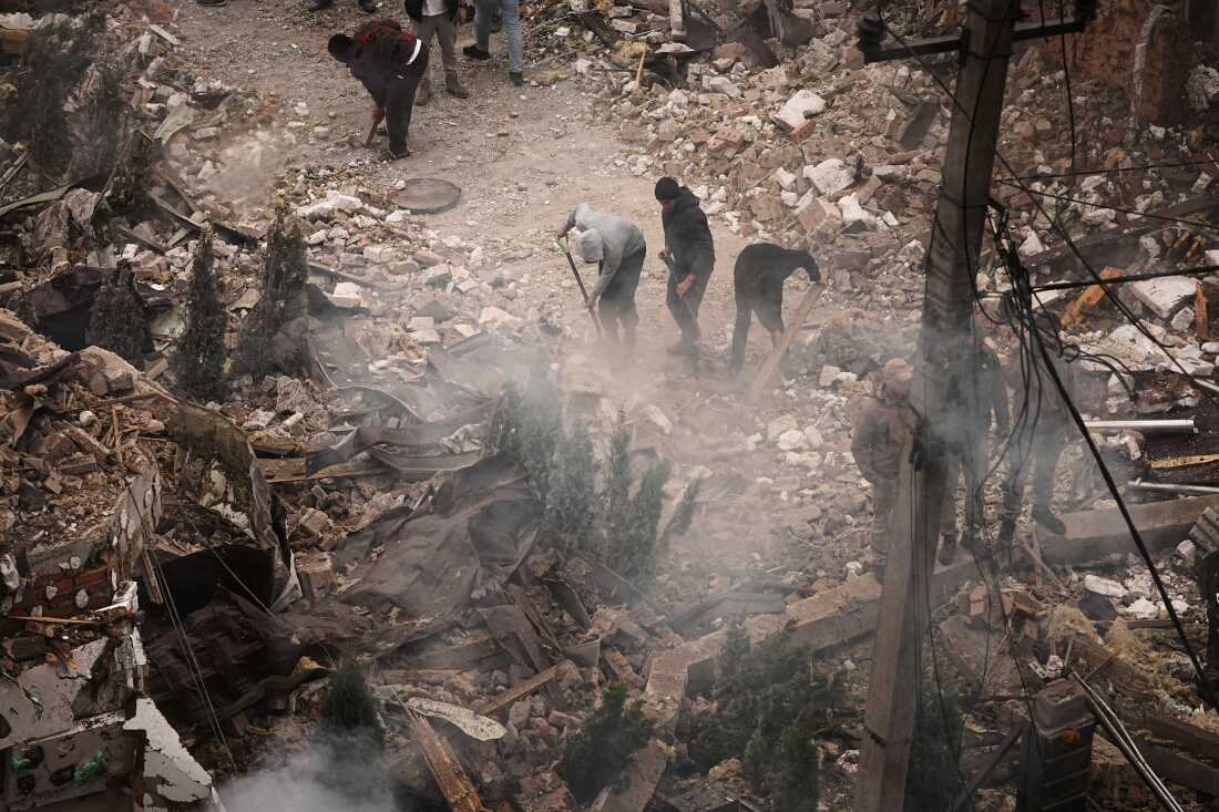 People clear debris at an apartment building damaged during a Russian attack in Kyiv, Ukraine, Sunday, Sept. 28, 2025.