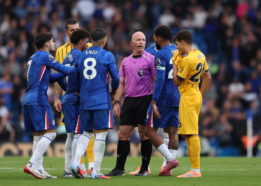 Chelsea players surround referee Simon Hooper during a Premier League match