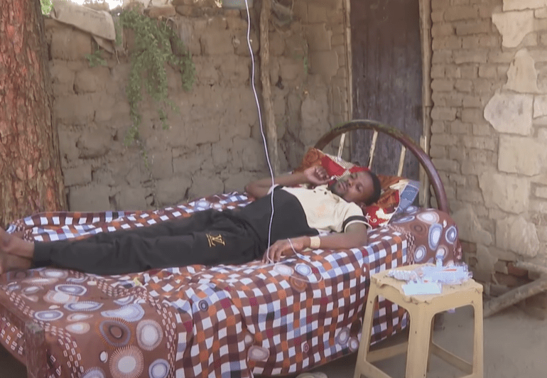A man lies down on a bed under a tree