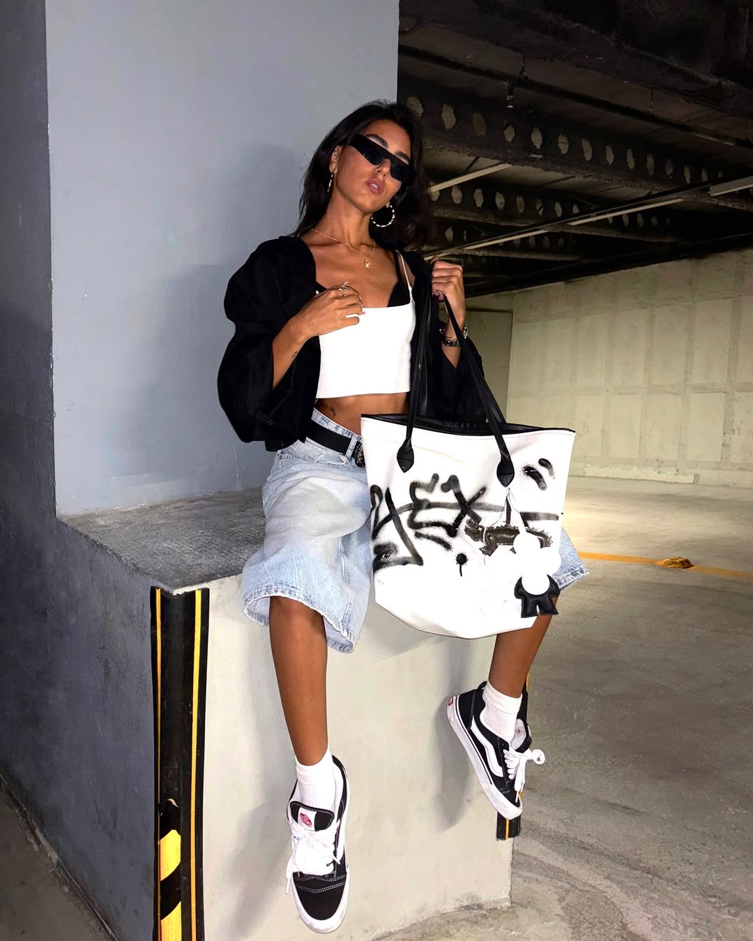 woman carrying black and white tote with bold bag charm accessory