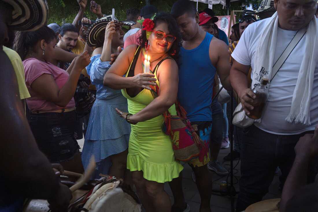 Ingrid Cifuentes dances with candles as gaitas and drums play and people dance cumbia in the main plaza on August 13, 2022, in San Jacinto, Bolívar, Colombia, during the Festival Nacional Autóctono de Gaitas. The gaita, a traditional cactus-made instrument, is closely linked to cumbia's origins.