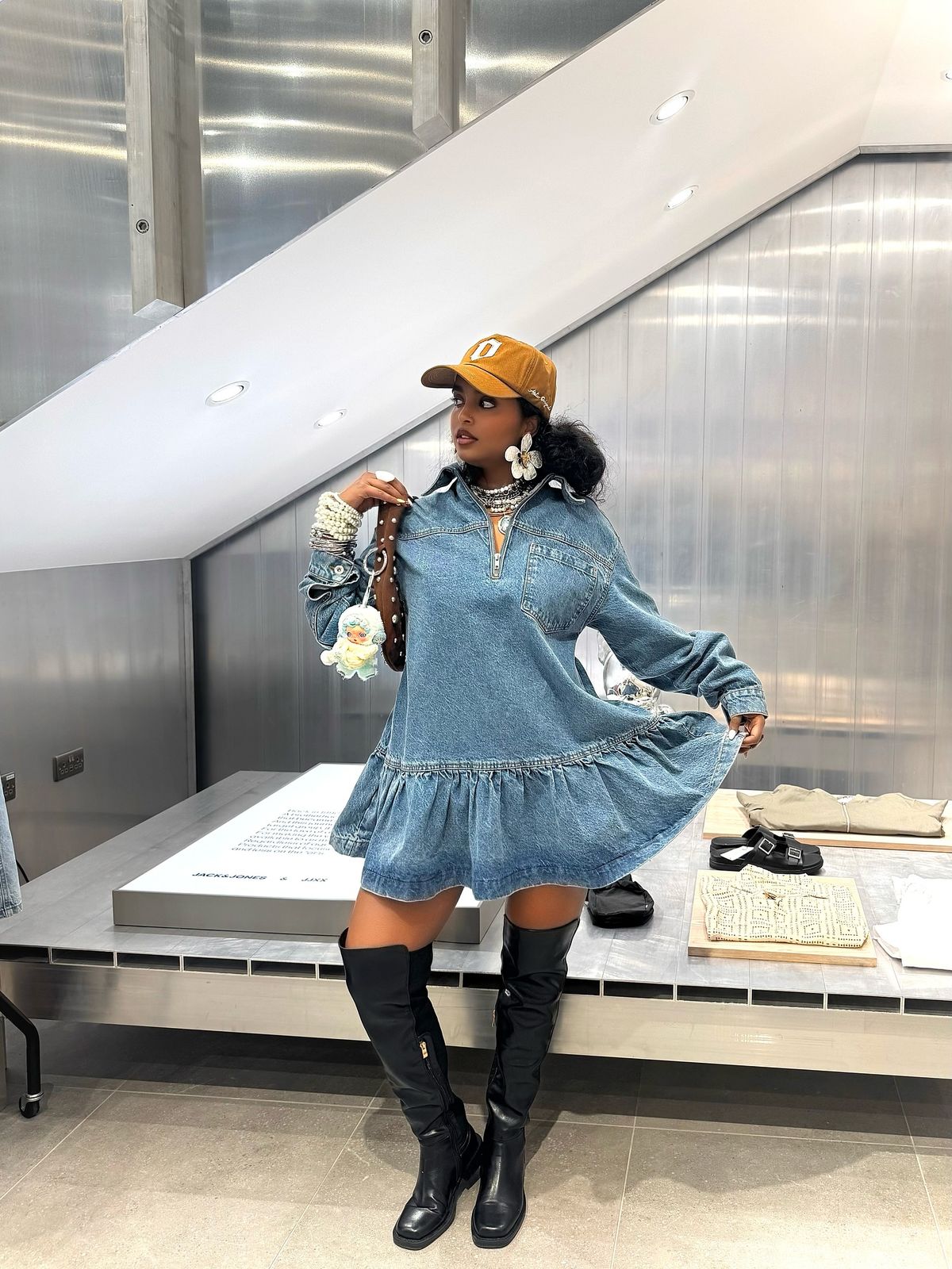 woman wearing mini modern denim dress with patent black boots and baseball hat