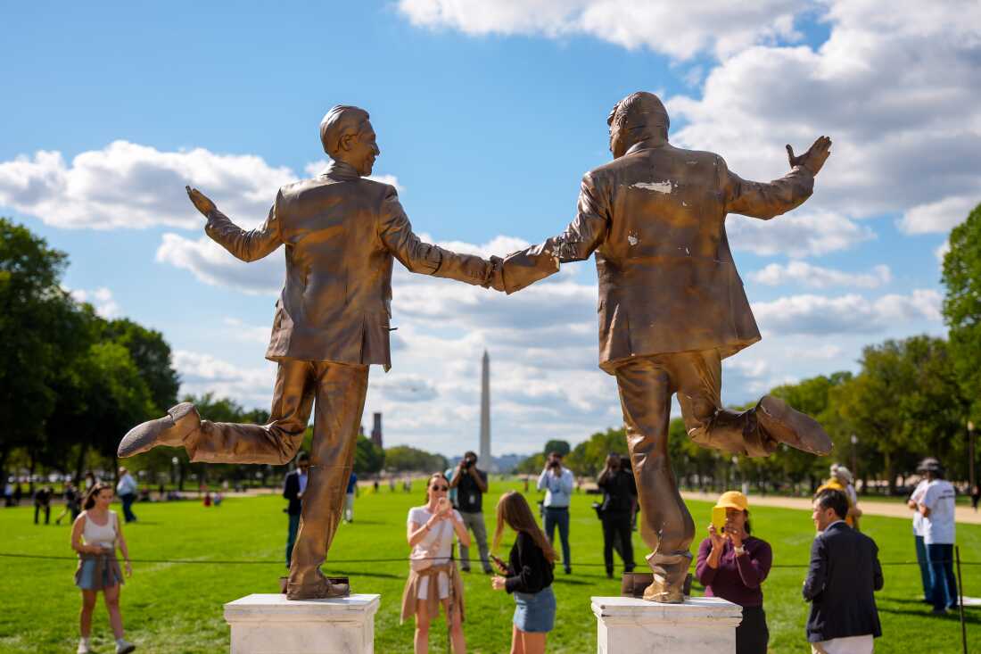 Visitors photographing the statue with the Washington Monument in the background