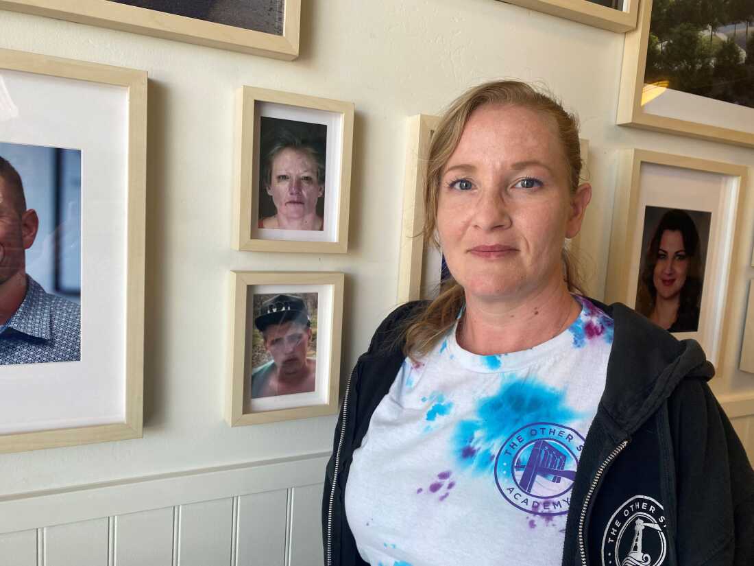 Coach Jackie Tress stands beside a photo of herself from when she first left homelessness.