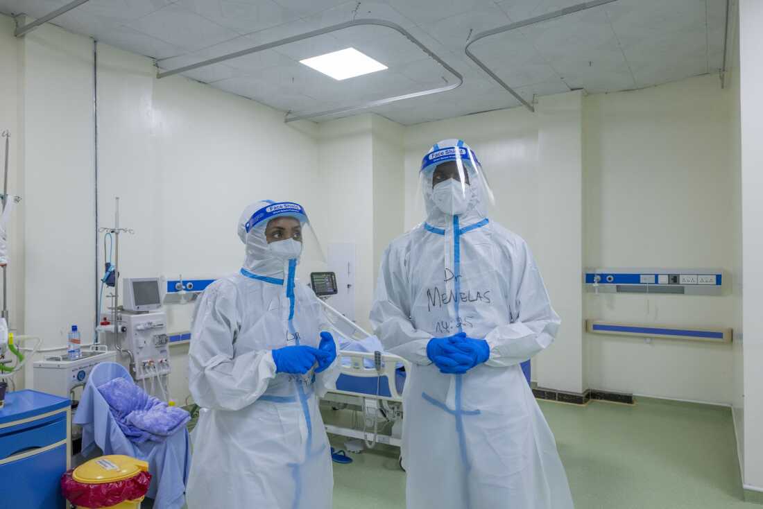 Dr. Tsion stands alongside Dr. Menelas in a Kigali treatment center for Marburg patients.