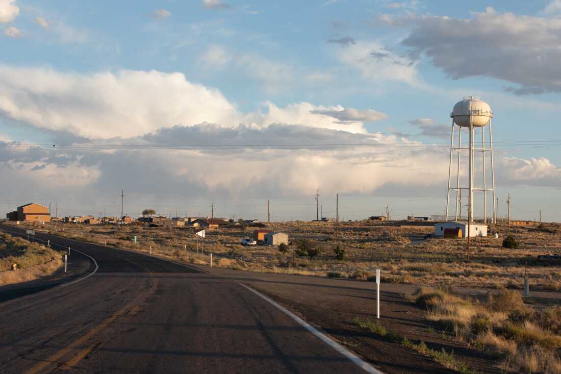 Sunlight over the village of Shongopovi with scattered buildings and a winding road