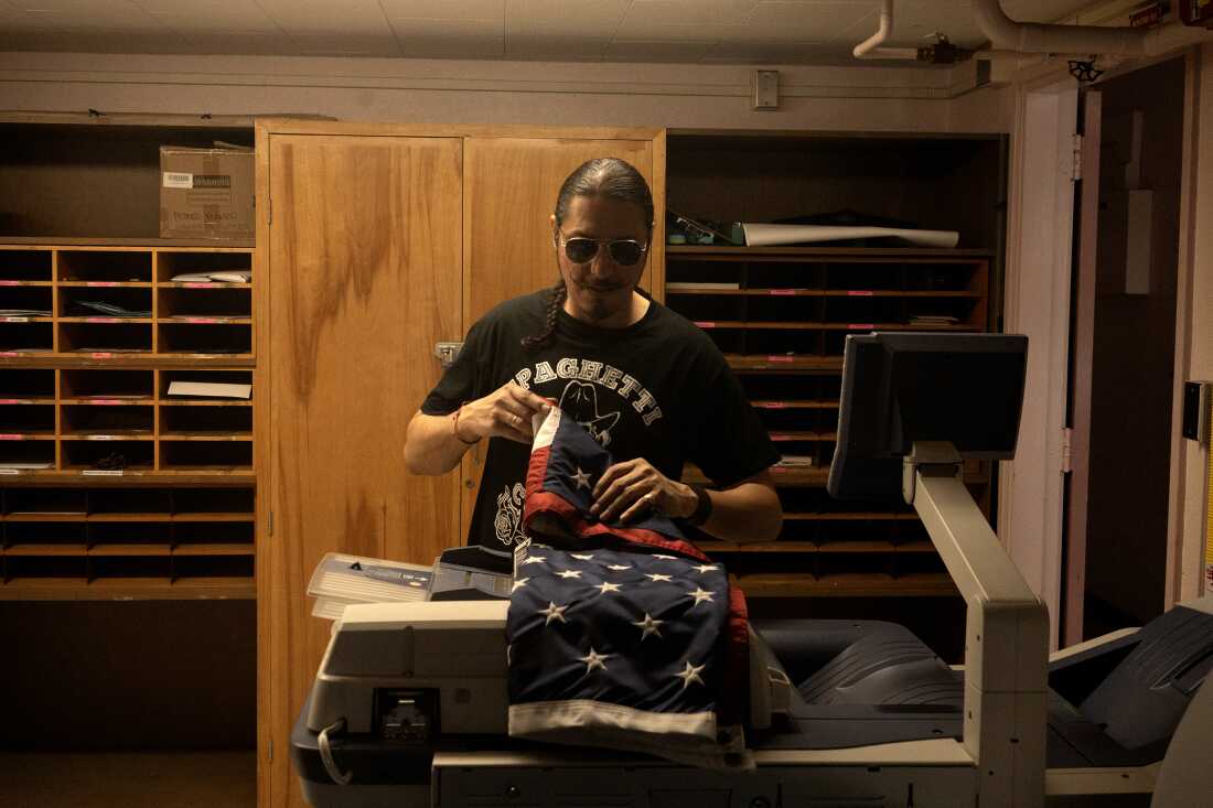 Bobby Guerrero doblando la bandera estadounidense en la escuela donde trabaja, mayo 2023.