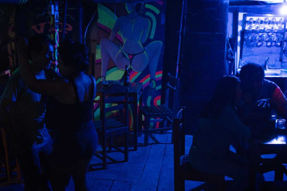 The walls of El Refugio, a bar in Iquitos, Peru, are adorned with art by José 'Ashuco' Araujo, an Amazonian chicha artist. Couples dance and converse in this venue known for live cumbia music on October 26, 2024.