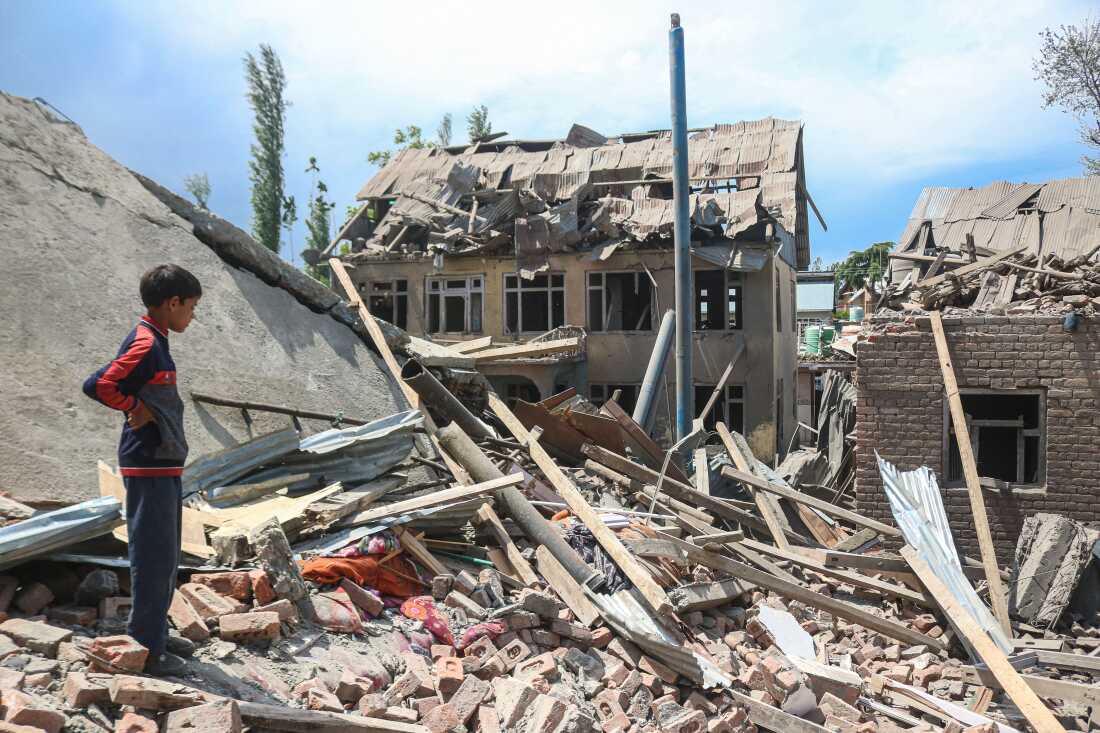 A child stands amid rubble of a demolished house linked to a suspected militant's family in Kashmir.