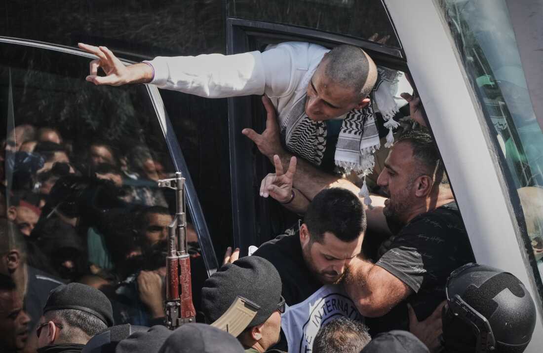 Palestinian prisoners wave after release in Ramallah following ceasefire.