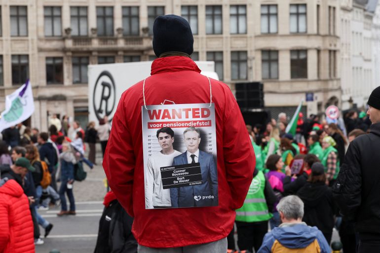 Protester holding a sign depicting Belgian Prime Minister Bart De Wever with the words 'Wanted for pension theft' during a strike in Brussels, October 14, 2025.