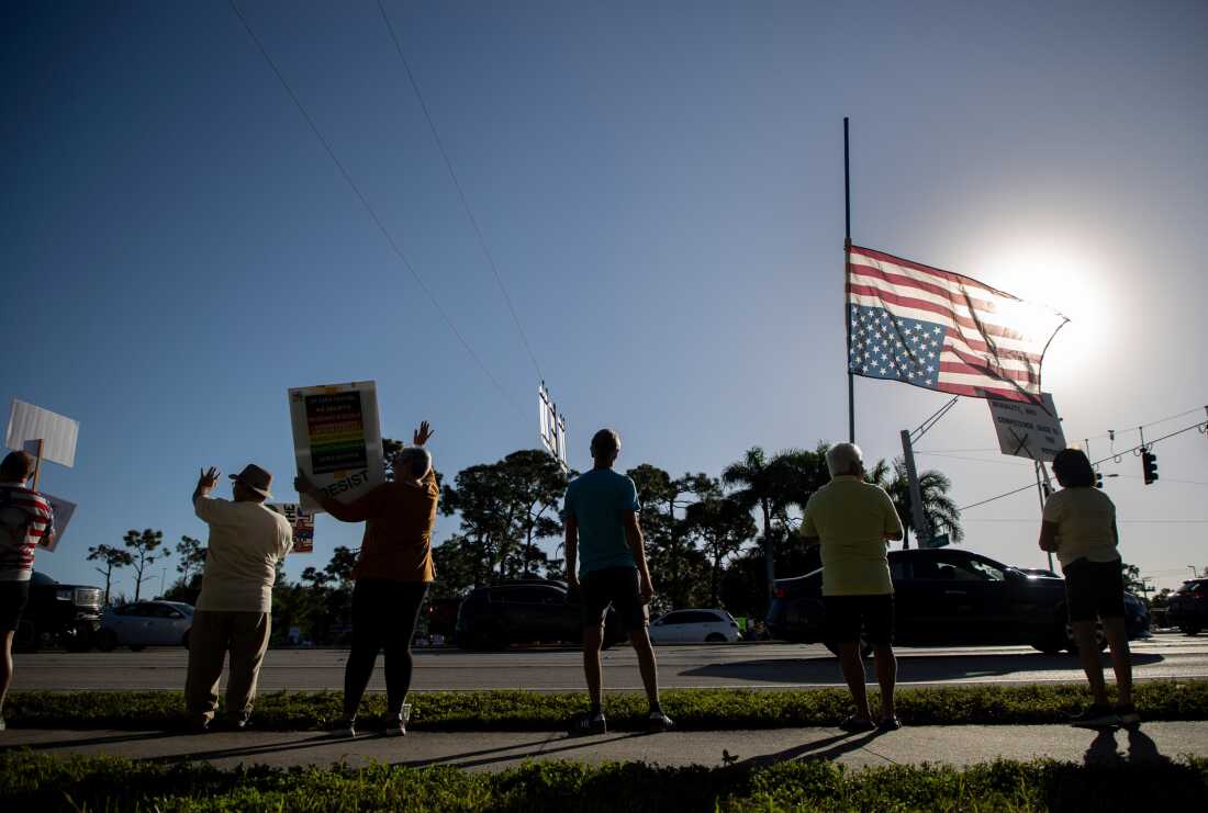 Protesters holding placards at the intersection of Daniels Parkway and U.S. 41 in Fort Myers.