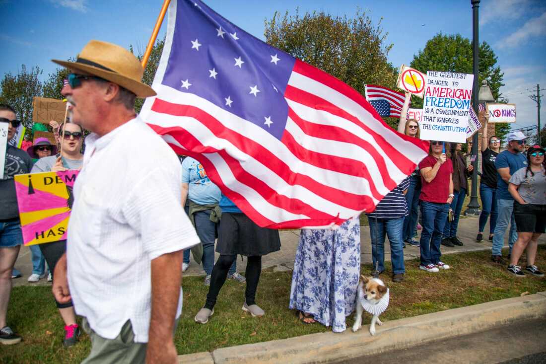 Joe Bondulich carrying a historic flag past a crowd on College Street in Macon, Georgia.