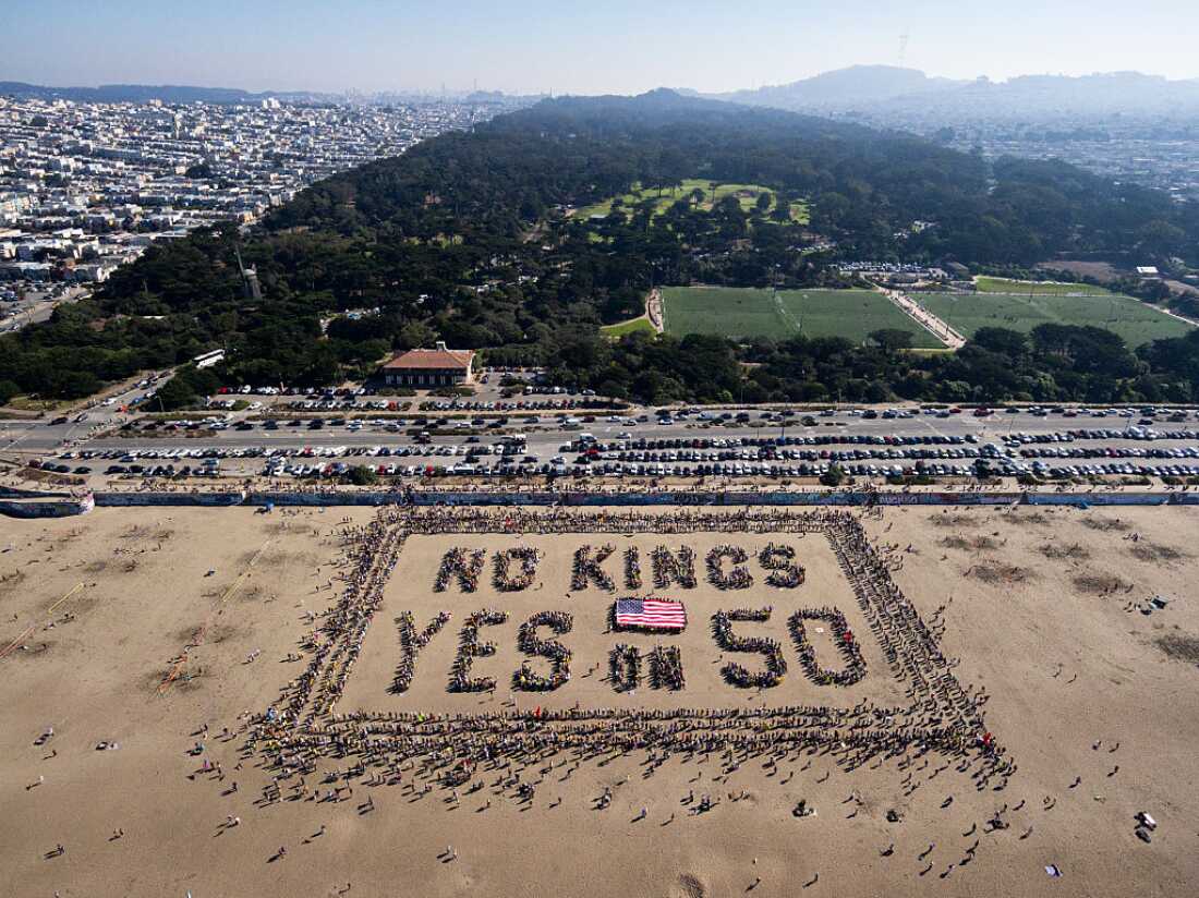 Aerial view of protesters forming a human banner on Ocean Beach, San Francisco during the 'No Kings' protests on October 18, 2025.