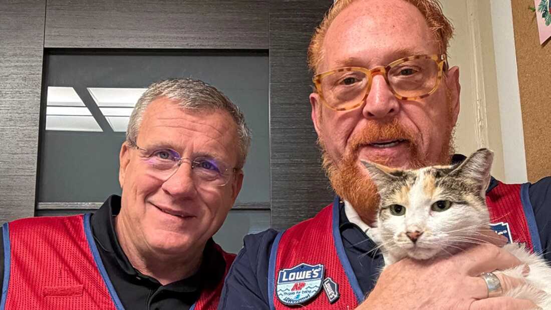 Mike Sida and Wayne Schneider pose with Francine the cat at a Lowe's in Richmond, Va.