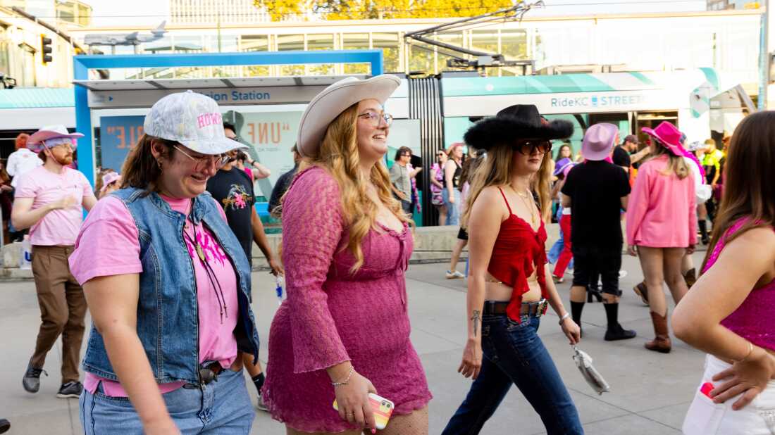 Fans wearing pink and cowboy hats disembark from a streetcar at Union Station before a concert.
